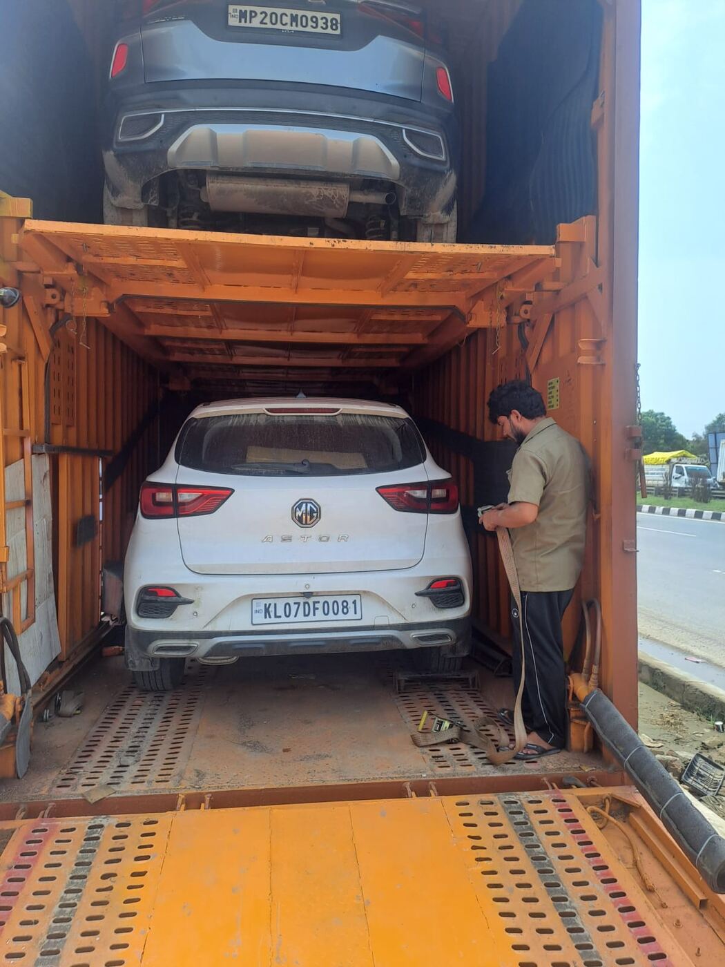 Car being loaded and strap-secured inside an Agrasen Trans Logistics enclosed car carrier